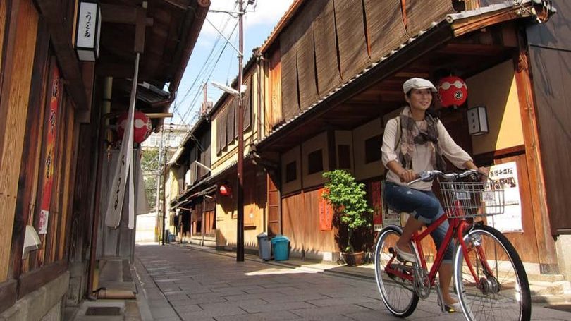 京都祇園の路地を自転車で走る女性